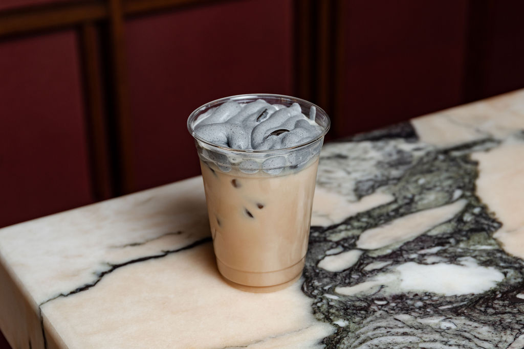 Iced latte with corn husk foam on marble