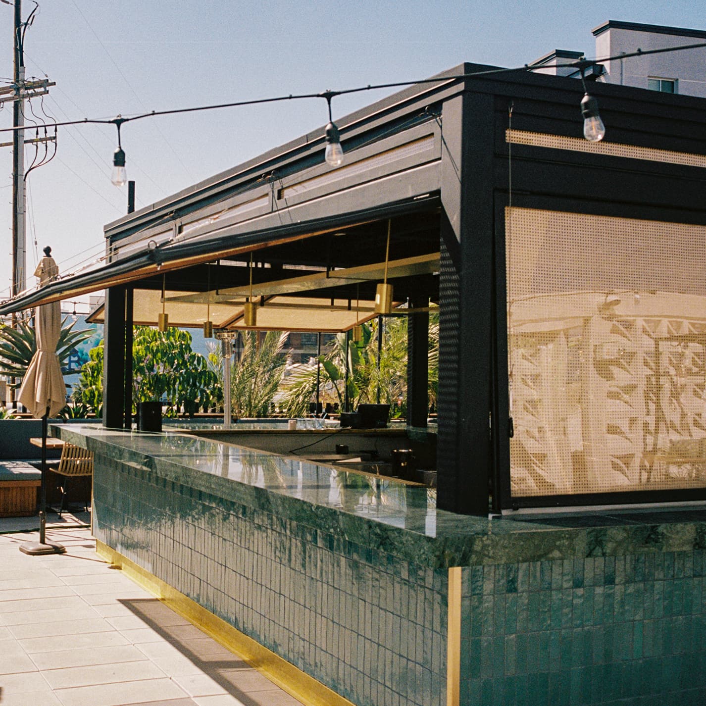 Rooftop ceviche bar counter under a black steel canopy