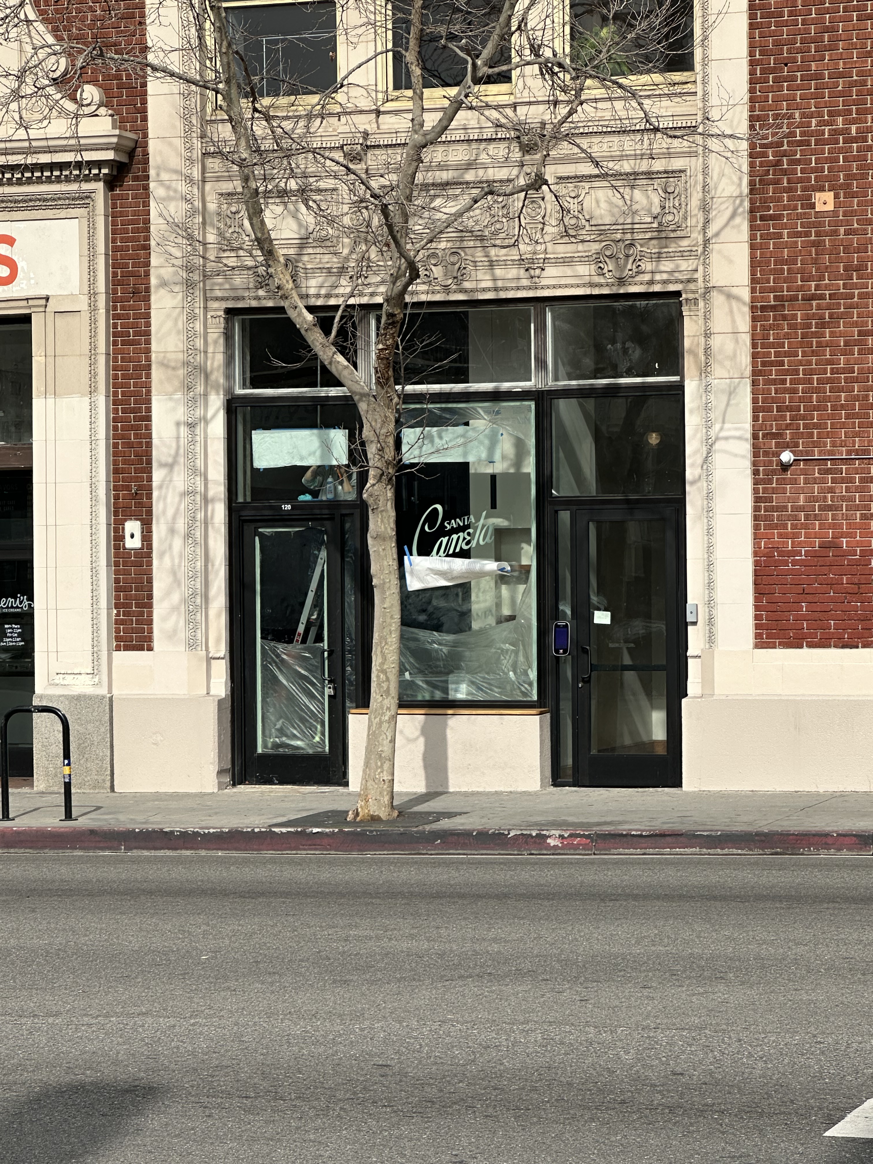 Santa Canela storefront during build-out with the script logo on the glass