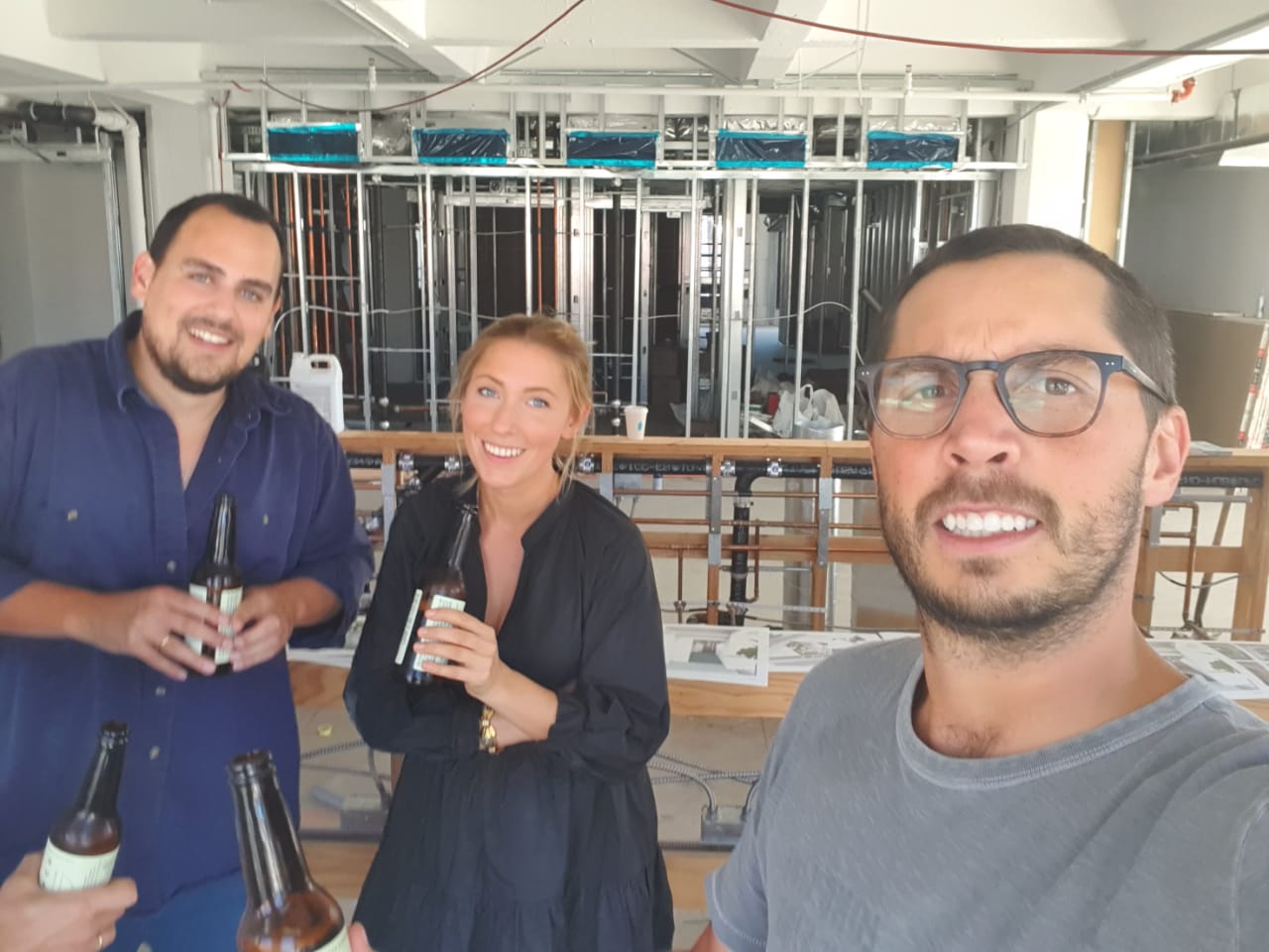 Founders toasting with beers inside a restaurant under construction